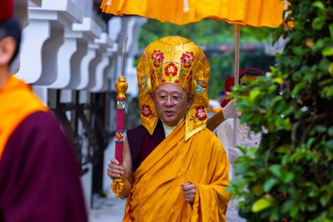 上師手持香棒在前引導弟子信眾頂戴大藏經繞寺